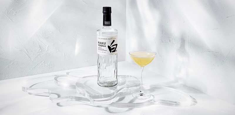 Haku Vodka Flasche mit Haku Yuzu Martini im Glas vor weißem Hintergrund