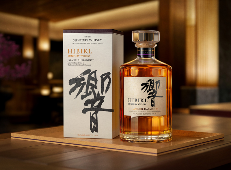 Eine volle Flasche Hibiki Japanese Harmony neben der Verpackung auf einem Holzbrett platziert auf einem Holztisch