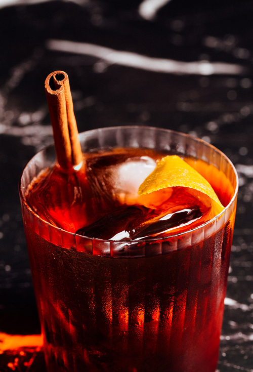 Maker's Mark Cocktail im Glas mit Eiswürfel, Zimtstange und Orangenzeste