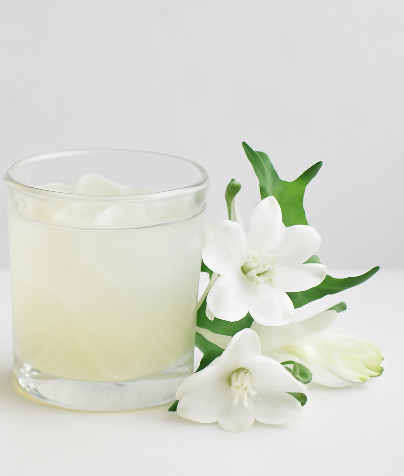 Roku Gin Garden Cokctail in einem Glas neben einem Zweig mit weißen Blumen