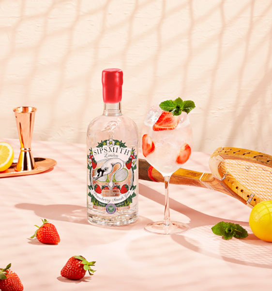 Sipsmith Strawberry Smash Gin Flasche mit Cocktail auf einem Tisch mit Erdbeeren und Tennisschläger