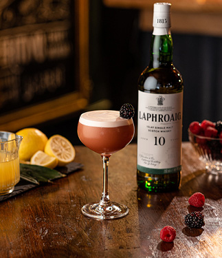 Smoky French Martini von Laphroaig im Glas neben einer Flasche Laphroaig 10 auf einem Tisch