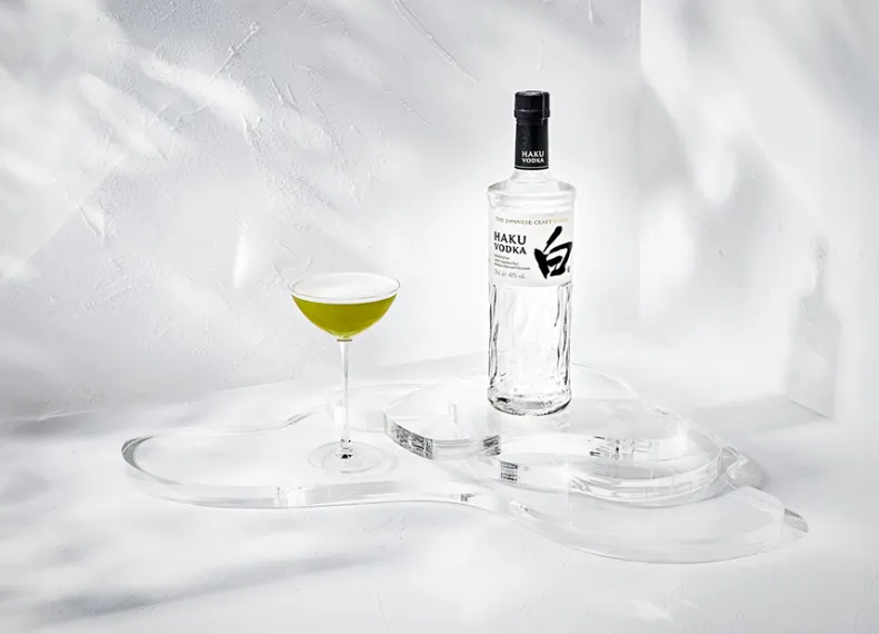 Haku Matcha Martini Cocktail im Glas neben einer Flasche Haku Vodka vor weißem Hintergrund