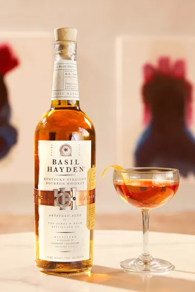 A bottle and a glass of Basil Hayden bourbon whiskey