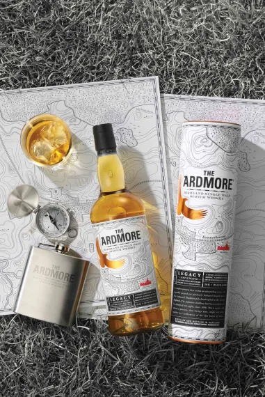A bottle of Ardmore Scotch whiskey, beside a hip flask and a glass of whiskey
