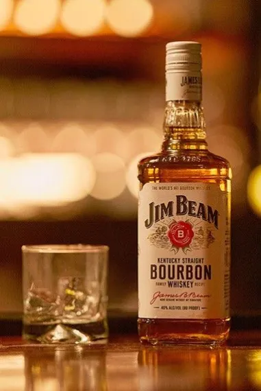 A bottle of Jim Beam whiskey beside a glass of whiskey