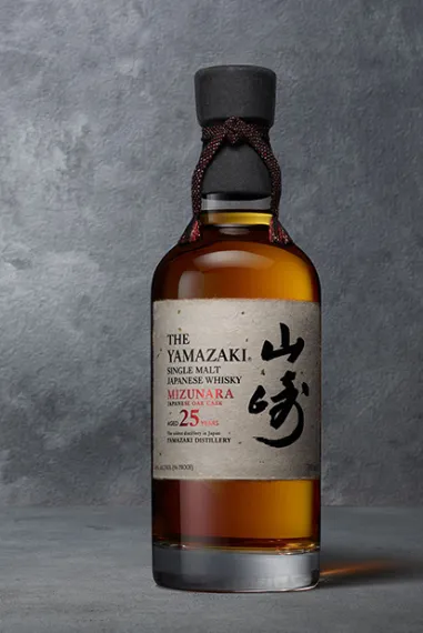 Eine Flasche aYmazaki 25 Years Old Mizunara vor einem dunklen grauem Beton-Hintergrund