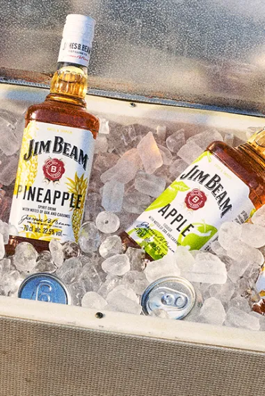 Jim Beam Pinapple mit den anderen Sorten Apple, Honey und Black Cherry in einer Kühlbox voller crushed Eis