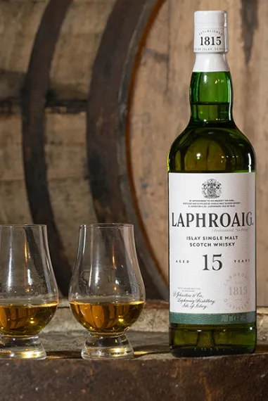 Laphroaig 15 Jahre - Flasche und zwei gefüllte Gläser auf einem Fass