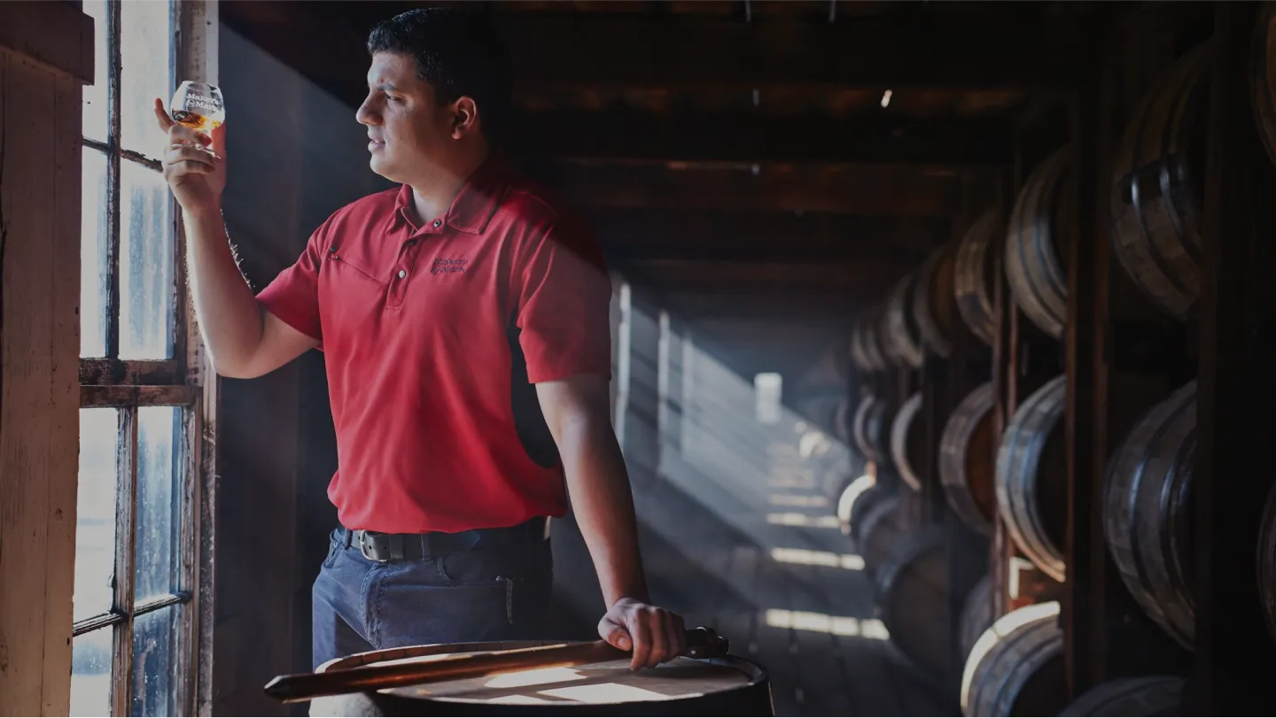 image of man holding Whisky glass inside Makers Mark distillery