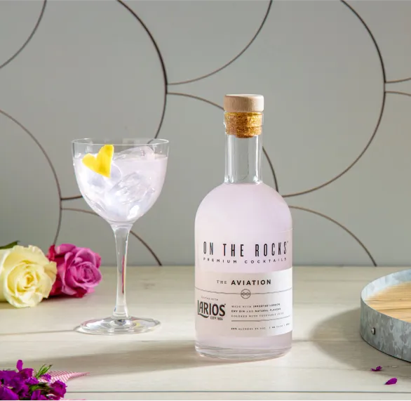 image of Ready to Drink On the Rocks bottle and filled cocktail glass placed on tabletop with roses
