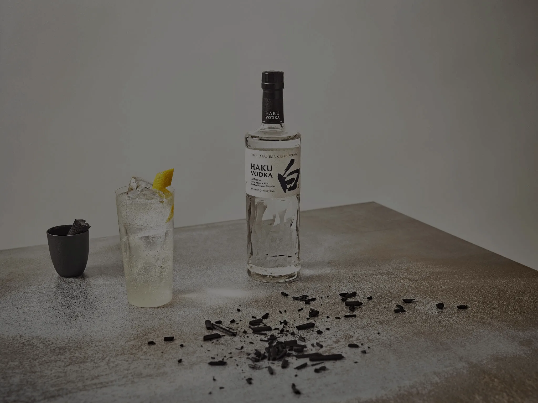 A bottle of Haku vodka next to a glass of vodka-based cocktail