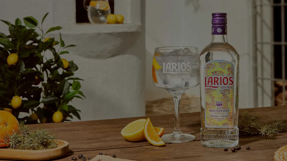 A bottle of Larios gin next to a glass of gin-based cocktail