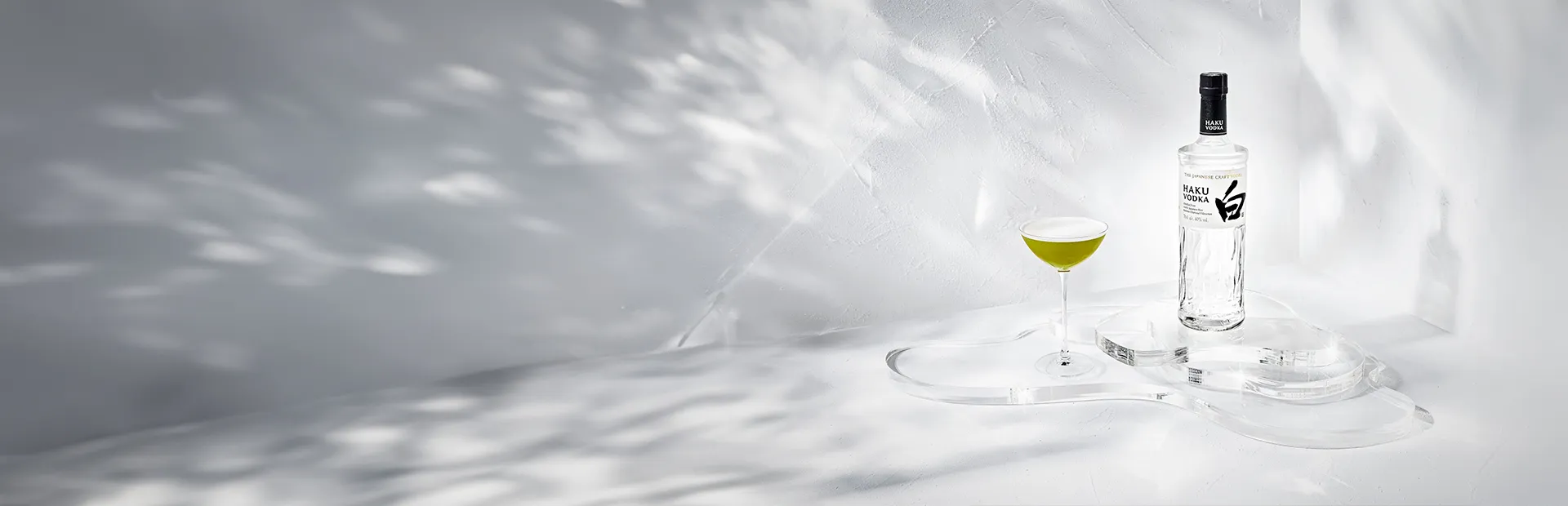 Haku Matcha Martini Cocktail im Glas neben einer Flasche Haku Vodka vor weißem Hintergrund