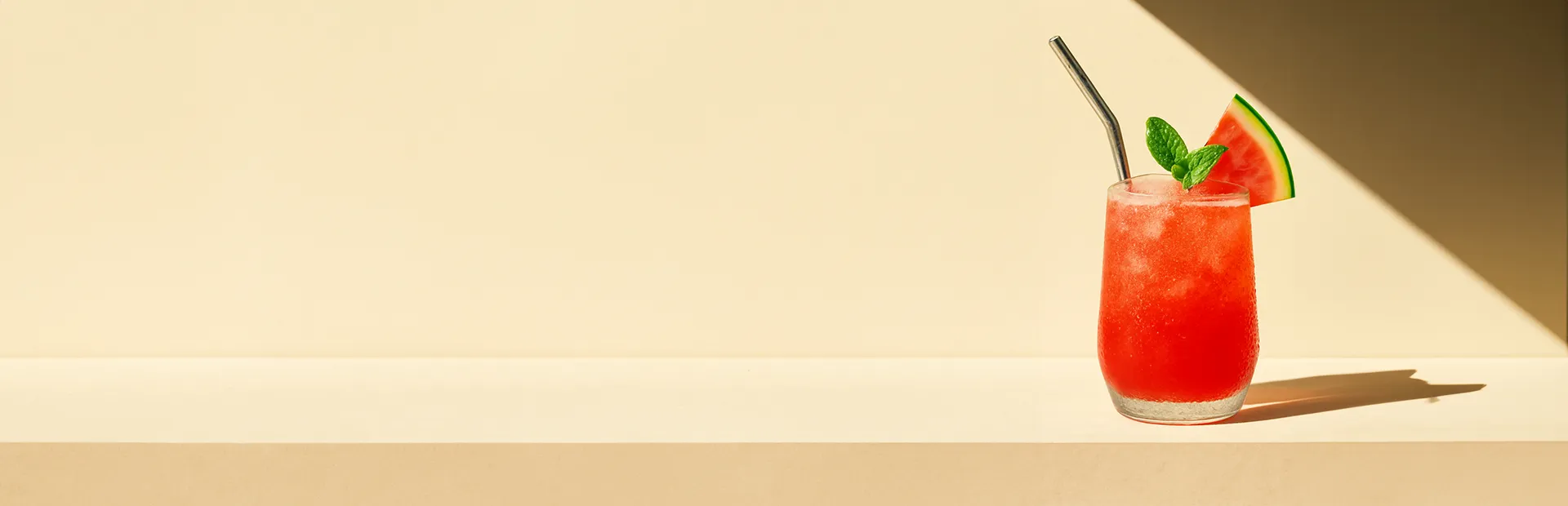 Roter Haku Velvet Sunset Cocktail in einem Glas, garniert mit Minzblättern und einer Melonenscheibe