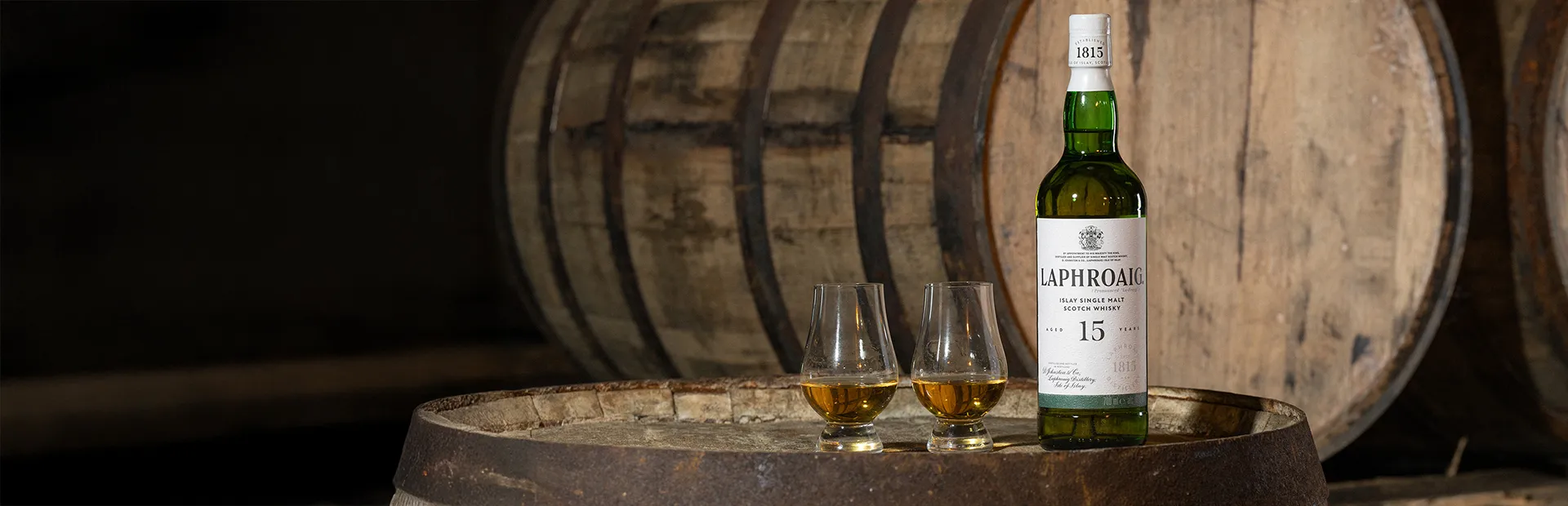 Laphroaig 15 Jahre - Flasche und zwei gefüllte Gläser auf einem Fass